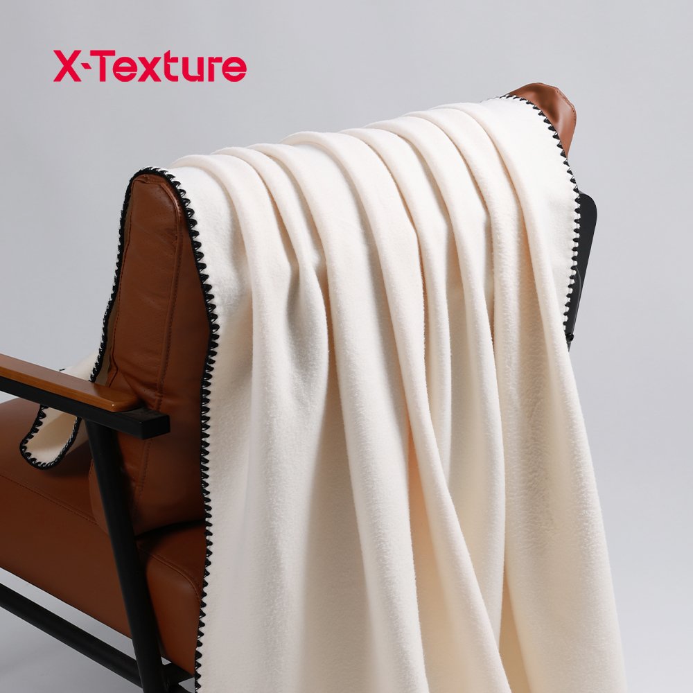 Cream white soft and warm double side fleece fabric draped over a chair with black binding.